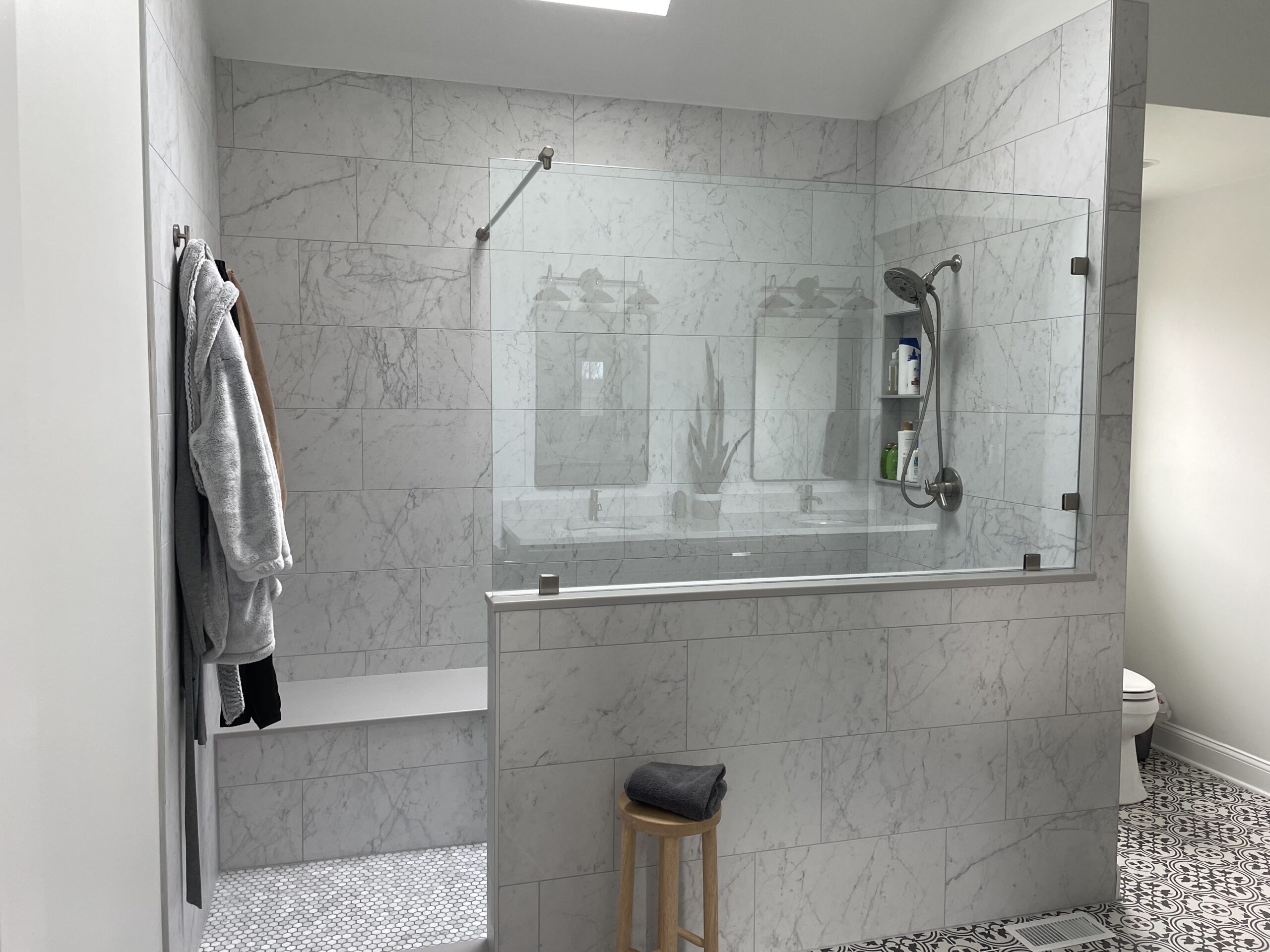 Classic bathroom remodel, folmar shower, large light colored wall tiles, shelves, traditional black and white floor tiles, toilet