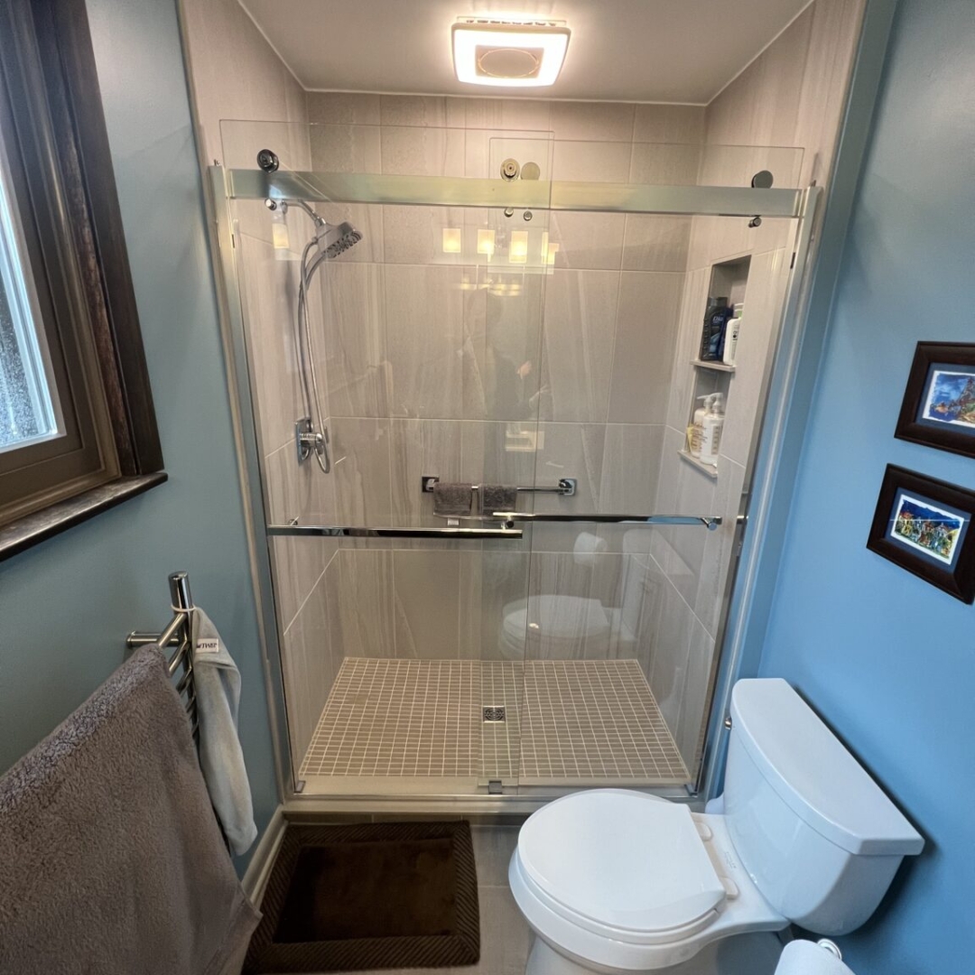 Classic blue bathroom remodeling, light gray shower tile walls, small beige square tile floor, two piece toilet toilet