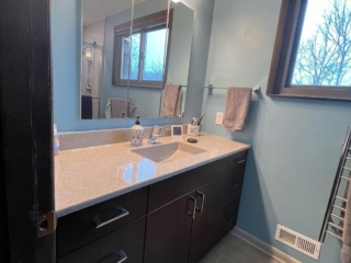 Classic bathroom remodel, light blue walls, light color marble countertop sink, dark cabinet storage, window