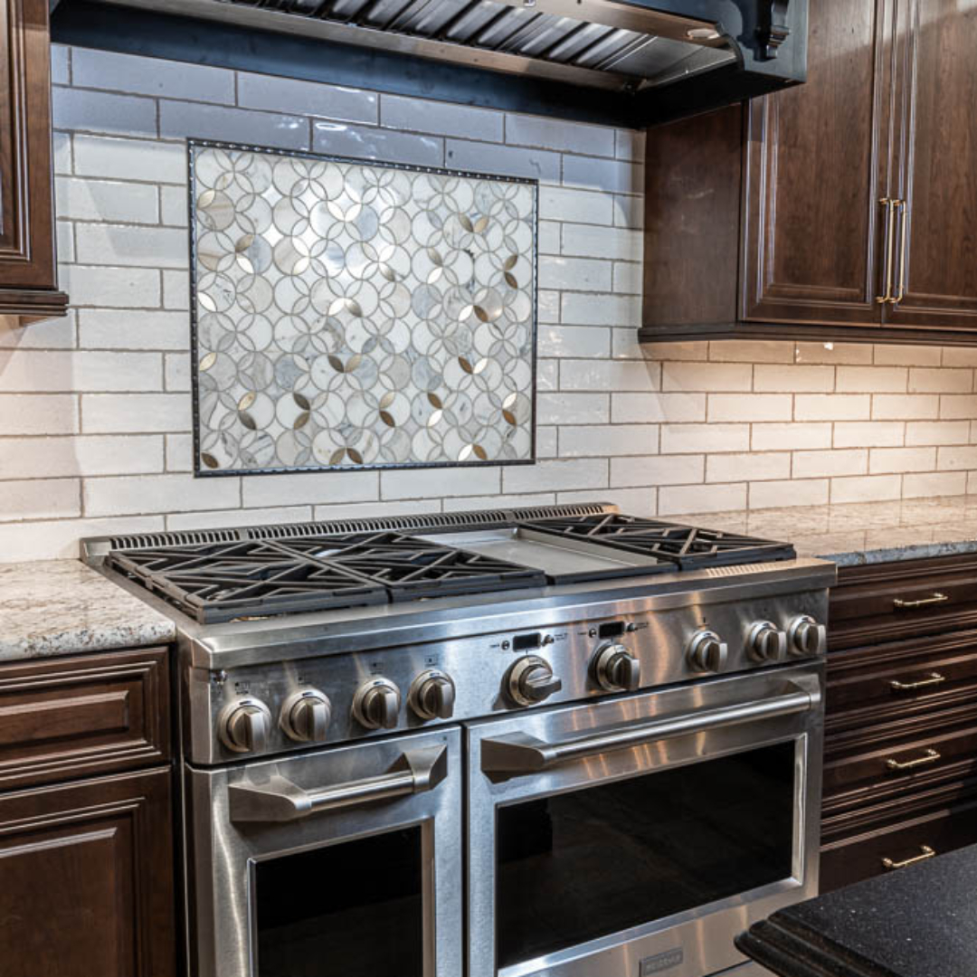 Traditional kitchen remodel, grey stove, traditional black vent hood, white tile backsplash, traditional brown cabinets, marble counter