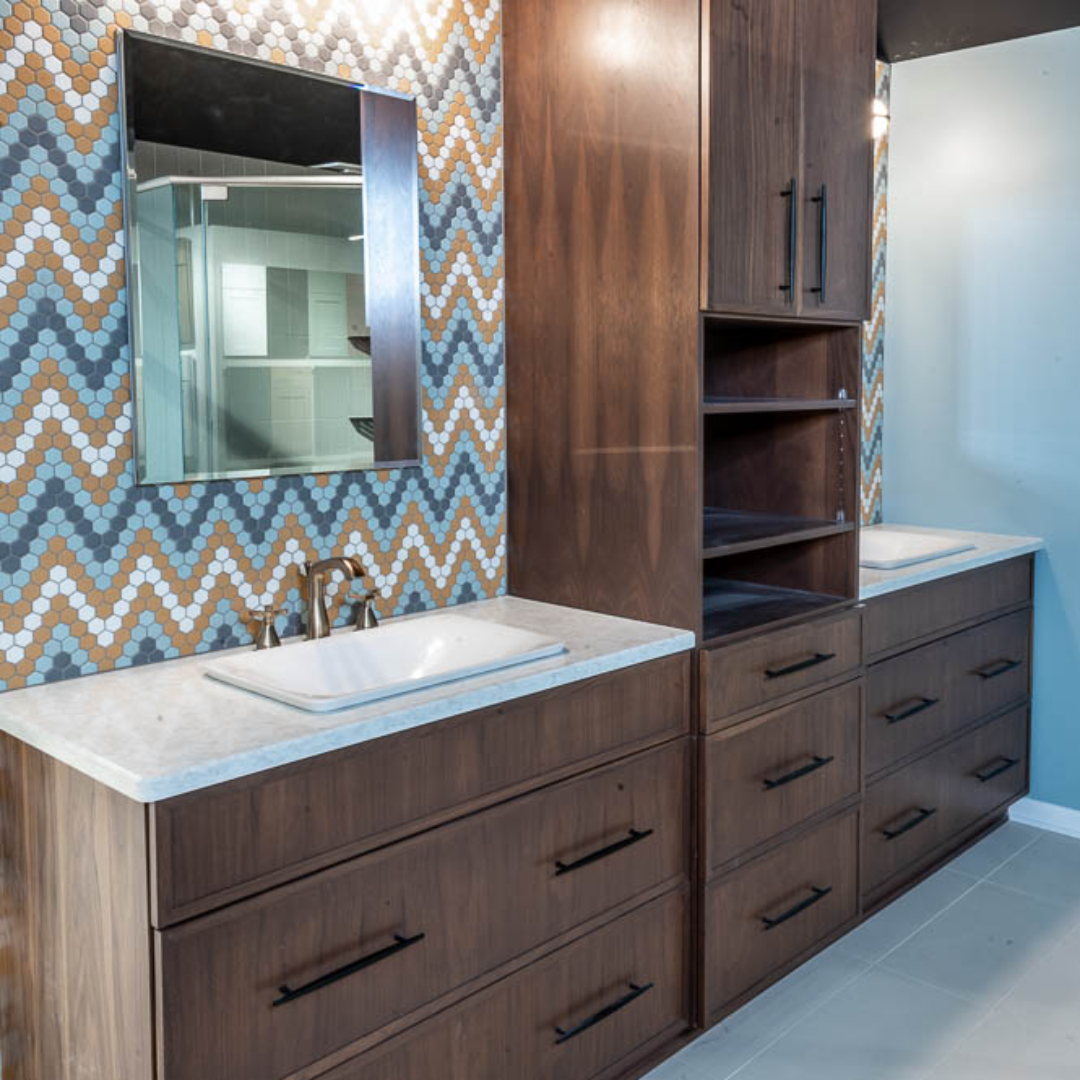 Traditional bathroom, two single sink with white marble countertop and brown wooden cabinets separated by a closet, large clean grey floor tiles