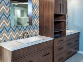 Traditional bathroom, two single sink with white marble countertop and brown wooden cabinets separated by a closet, large clean grey floor tiles