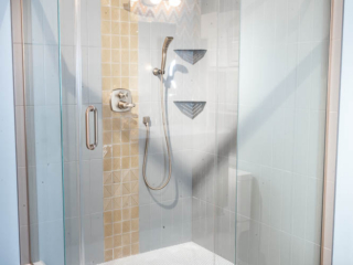 Traditional bathroom, large shower, small shelves, grey tile wall with column of yellow squared tiles
