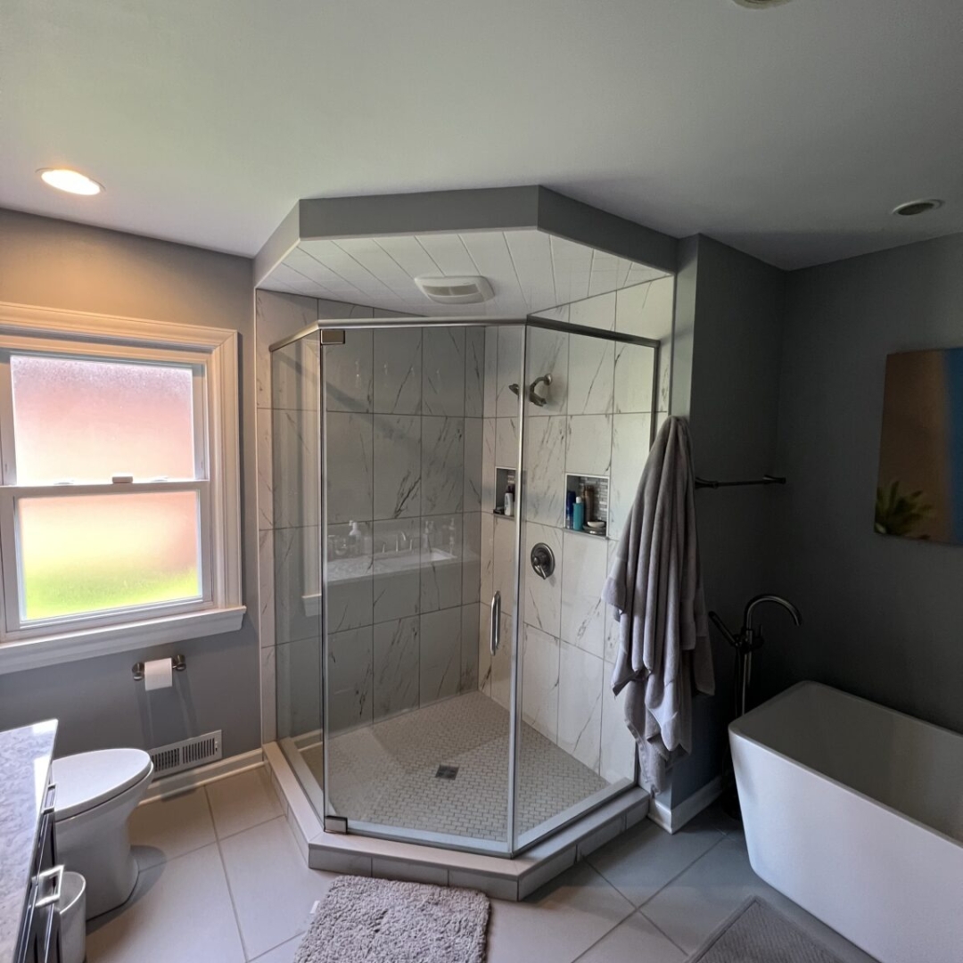 Contemporary bathroom, big shower with large light colored marble tiles, white soaking tub, blurry window