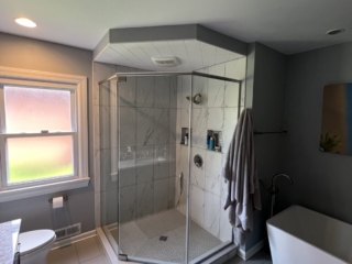 Contemporary bathroom, big shower with large light colored marble tiles, white soaking tub, blurry window