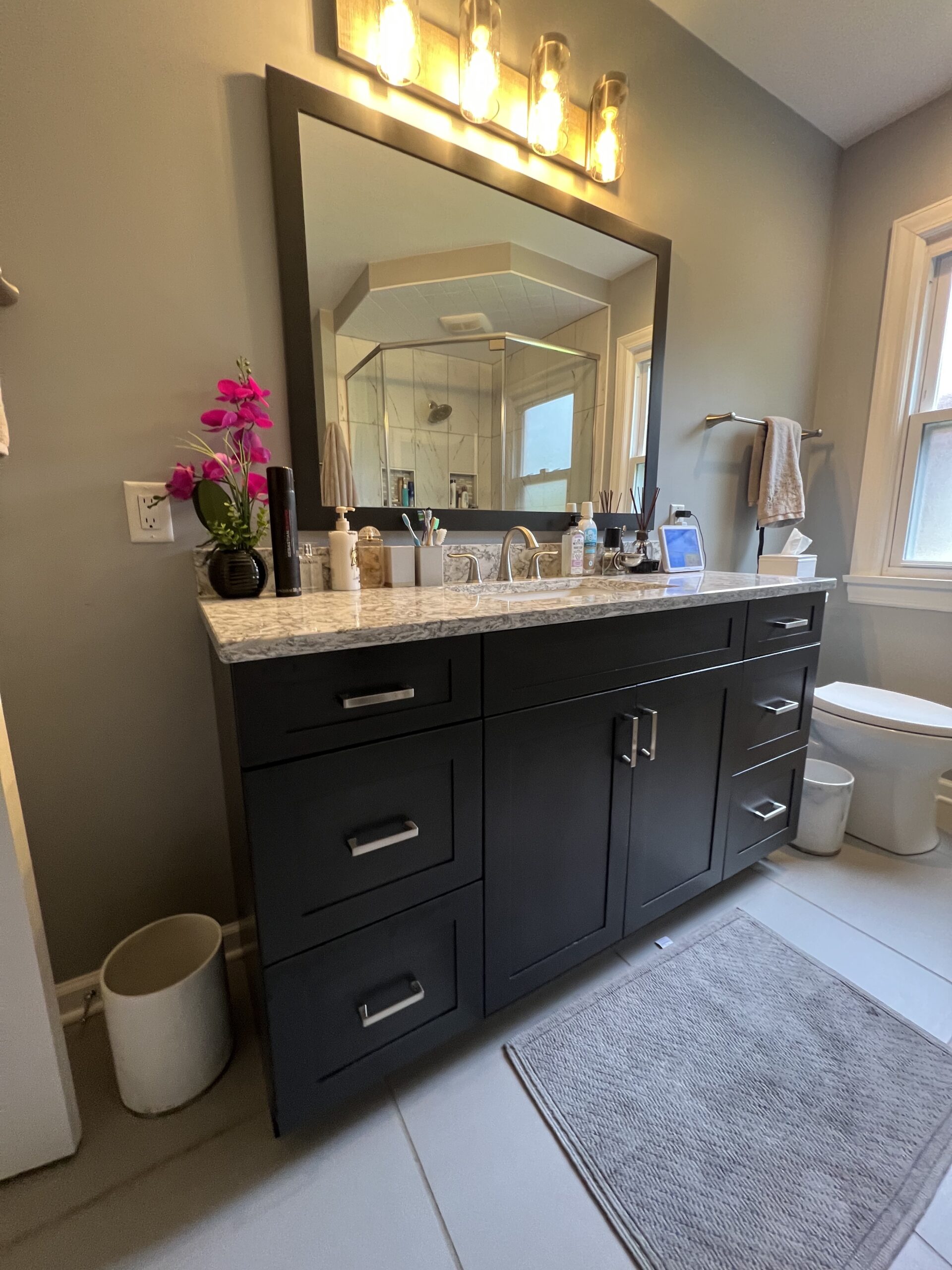Contemporary bathroom, white marble countertop sink, black cabinet storage, one-piece toilet, blurry window