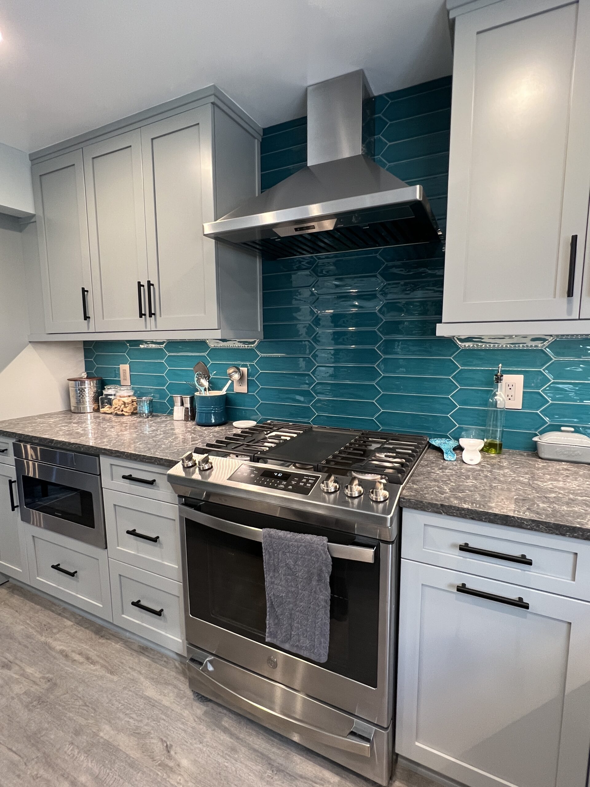 Classic full kitchen remodel, blue teal tiles, grey stove, little grey marble island, storage cabinets, spacious counter