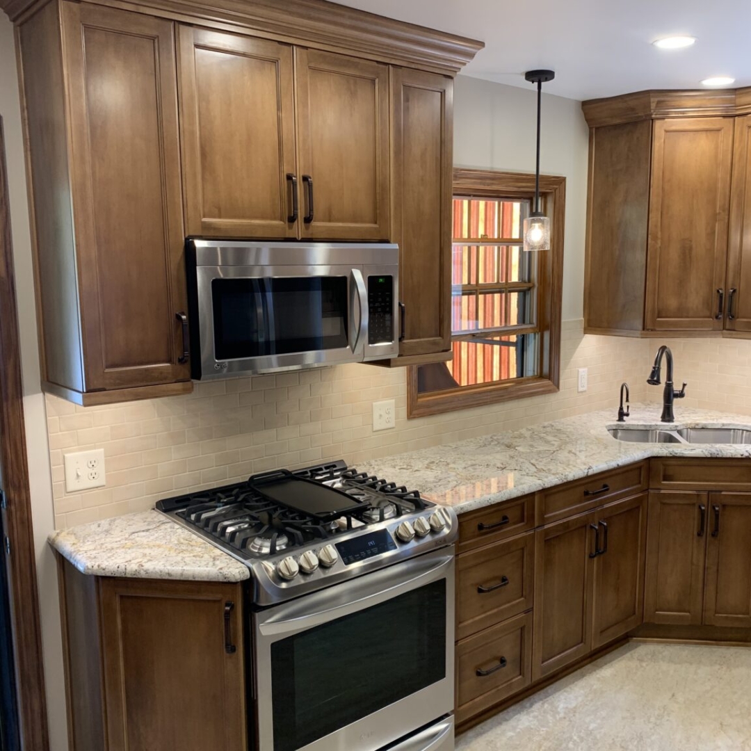 Traditional small kitchen remodel, marble counter, brown cabinets, black kitchen faucet, stove, microwave, window