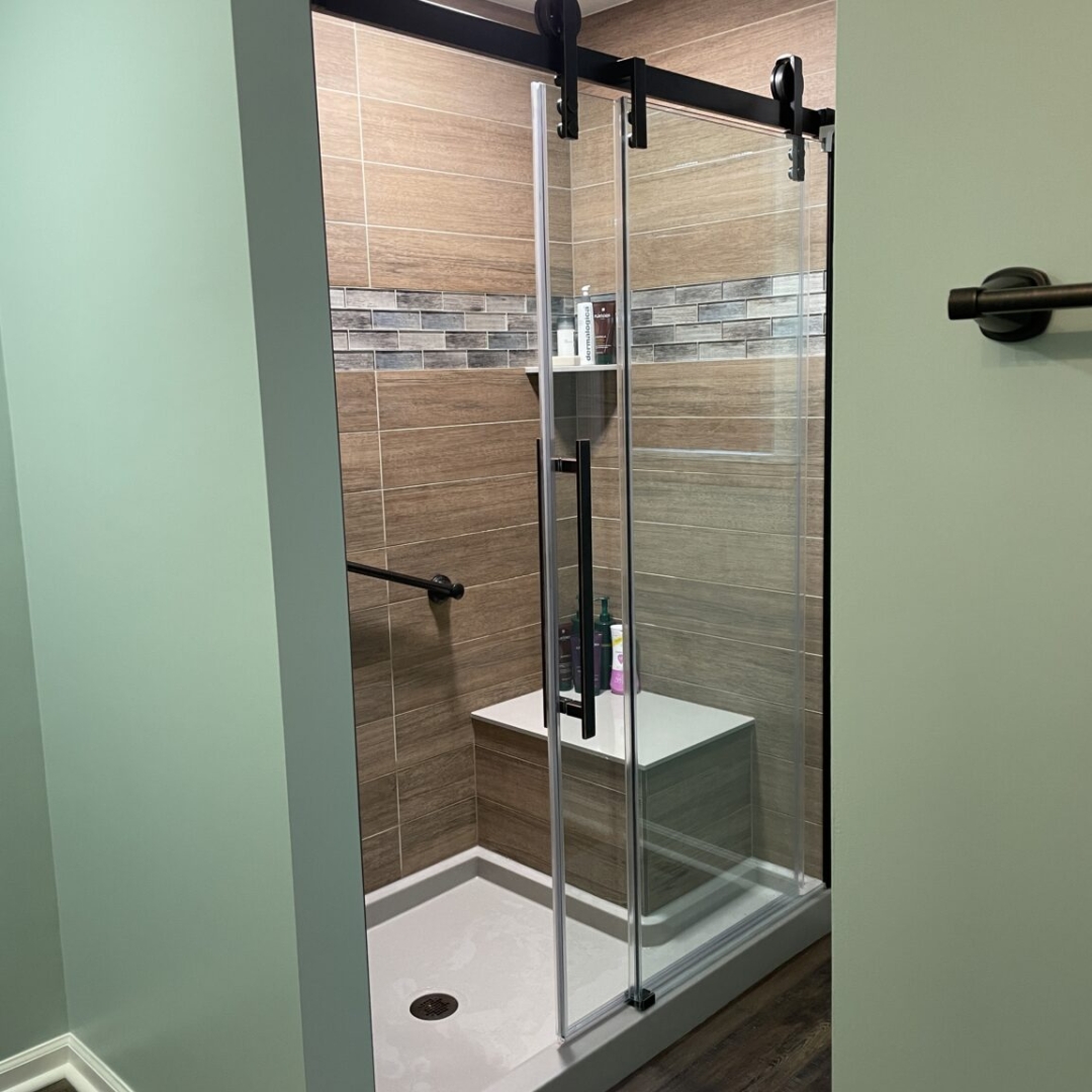 Contemporary green bathroom, brown shower tiles, black shower frame, grey marble shower strap