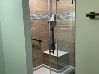 Contemporary green bathroom, brown shower tiles, black shower frame, grey marble shower strap