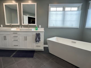 Contemporary bathroom remodel, expansive bath tub and 2 sinks with white marble countertop, white cabinets modern grey floor tile