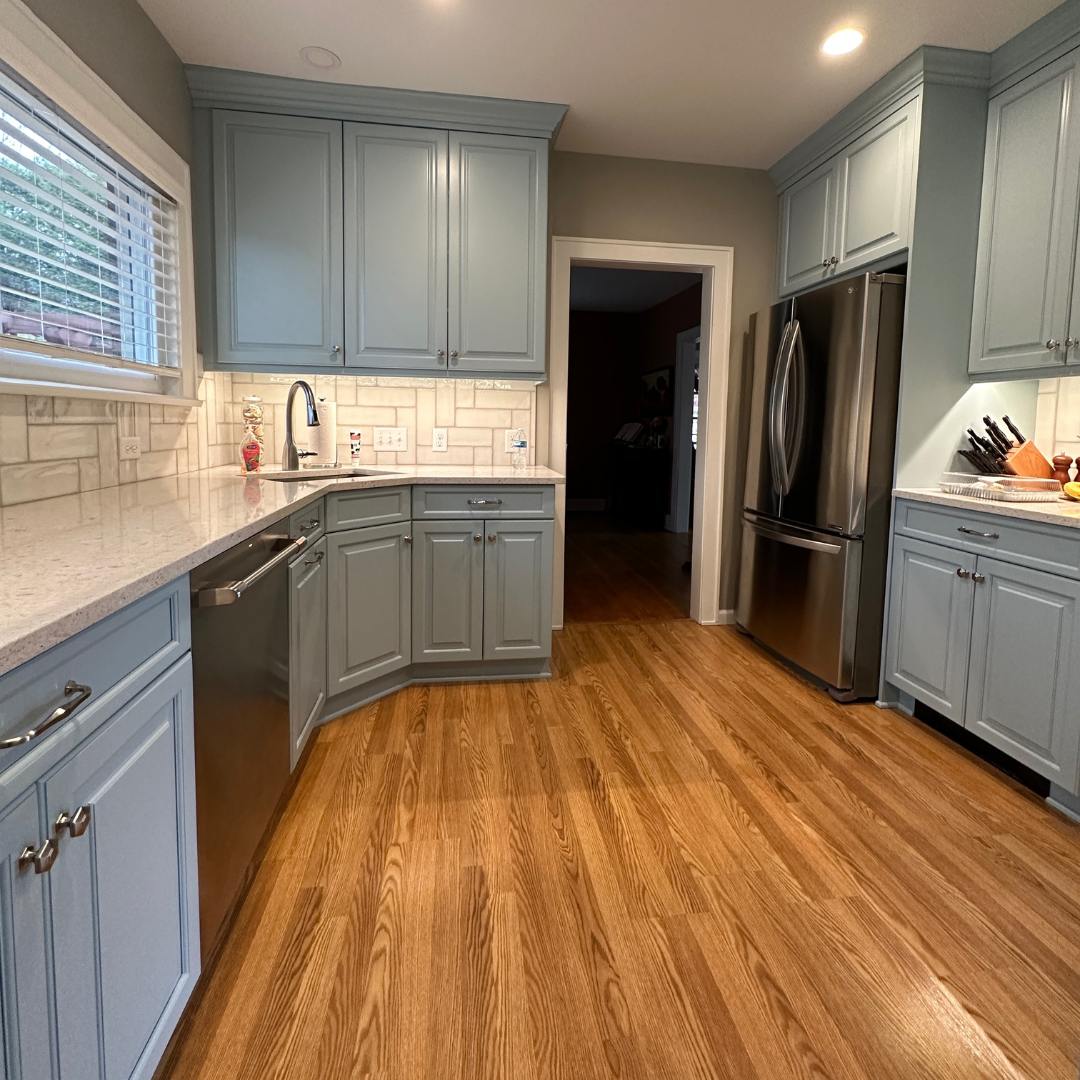 Traditional small kitchen remodeling with wooden floors and blue storage cabinets, white marble countertop, brown wooden floor tiles, butlers pantry