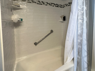 Traditional small bathroom remodel with classic white bathtub/shower, small shelves, black and white floor tiles