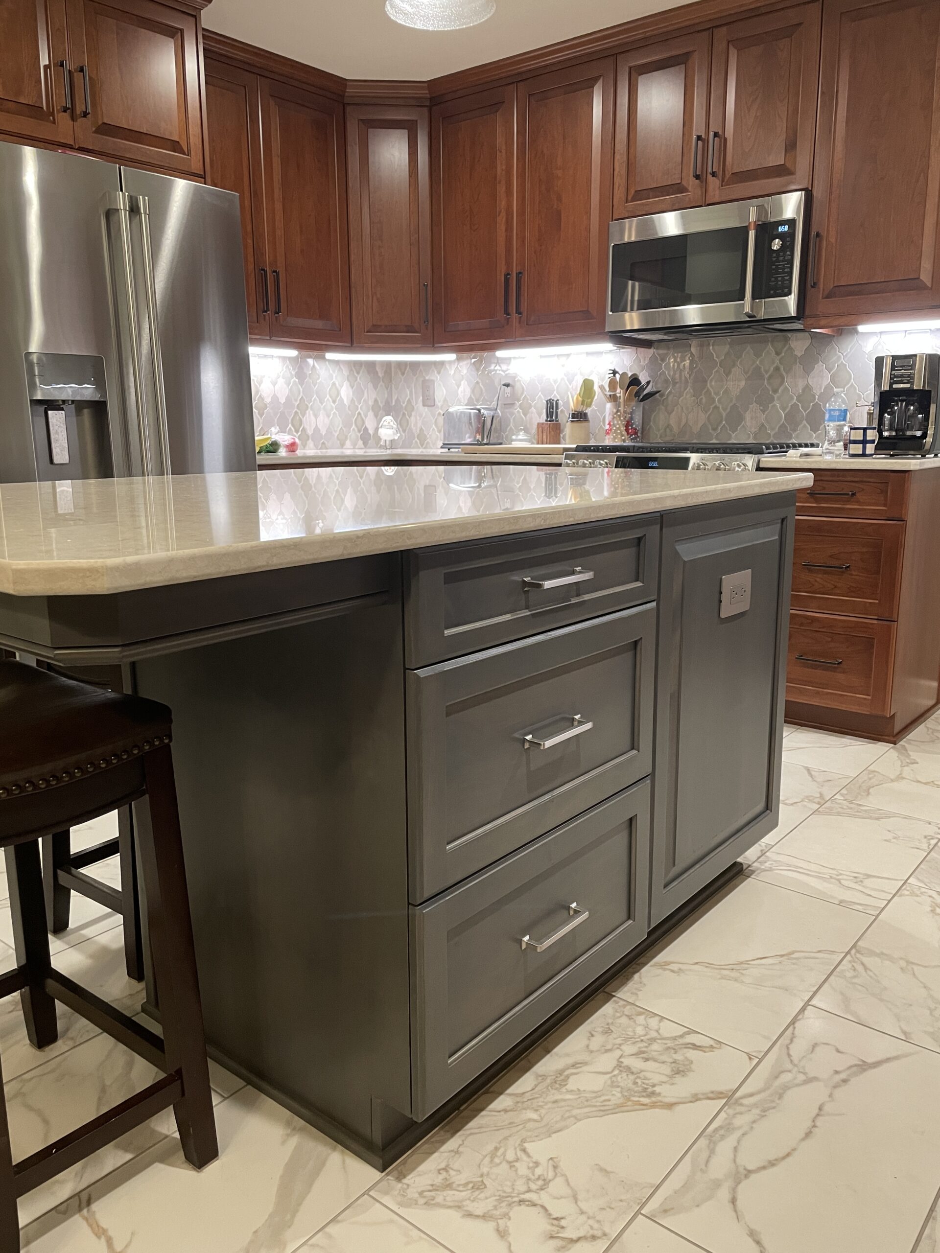 Classic kitchen, center island with white marble countertop, dark island drawers, brown cabinets and storage, arabesque tile backsplash, black and white floor tiles