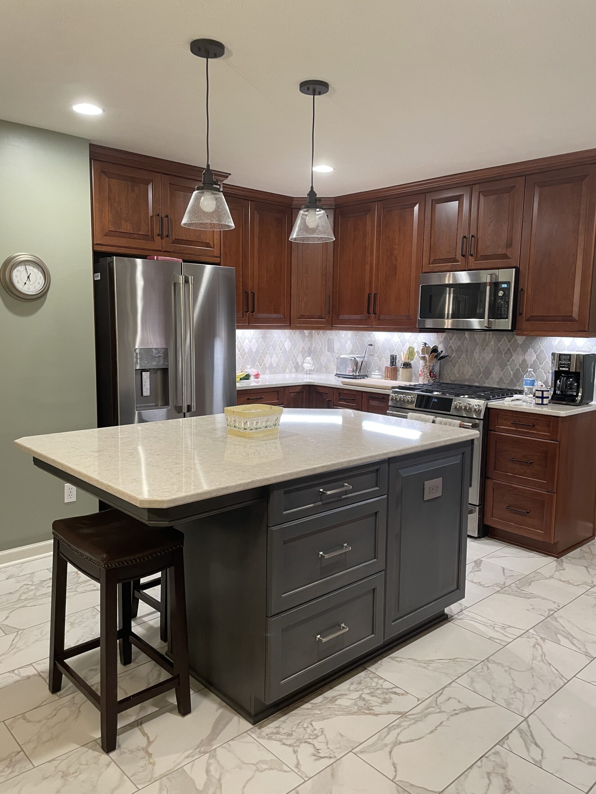 Classic kitchen, center island with white marble countertop, dark island drawers, brown cabinets and storage, arabesque tile backsplash, black and white floor tiles, light green wall
