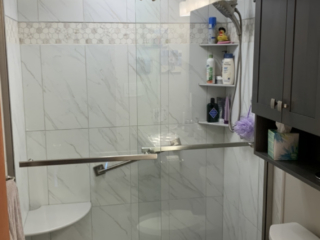 Classic small bathroom remodel, white marble tile shower walls, shower shelves, toilet