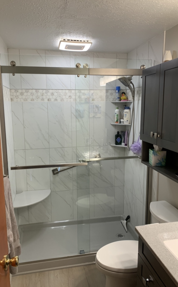 Classic small bathroom remodel, white marble tile shower walls, shower shelves, toilet