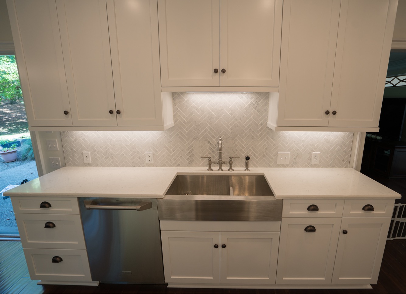 Classic white kitchen, farming sink, white countertop, white wall and base cabinets, light colored modern backsplash tiles