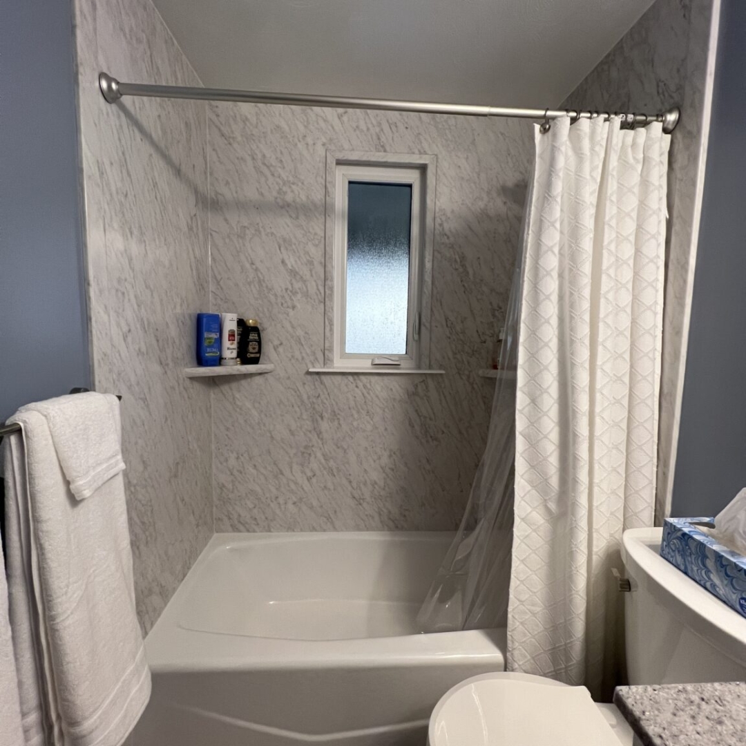 Classic small bathroom, shower and bathtub, blue wall, black and white marble shower walls, two-piece toilet