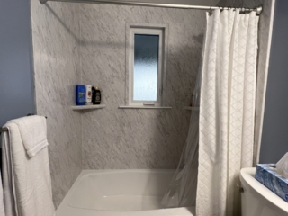Classic small bathroom, shower and bathtub, blue wall, black and white marble shower walls, two-piece toilet