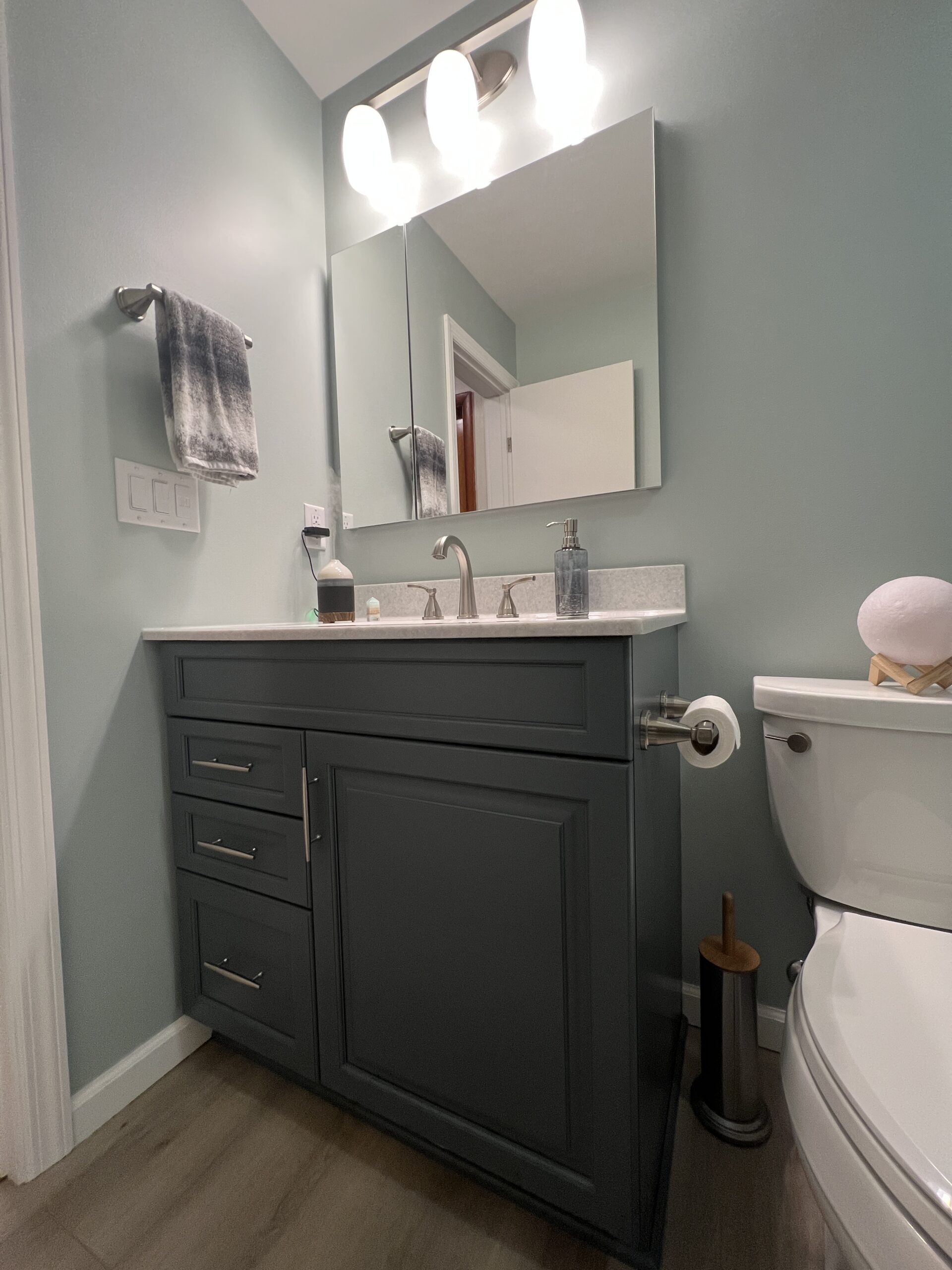 Modern green bathroom, small single single sink, dark cabinet storage, white marble countertop sink toilet