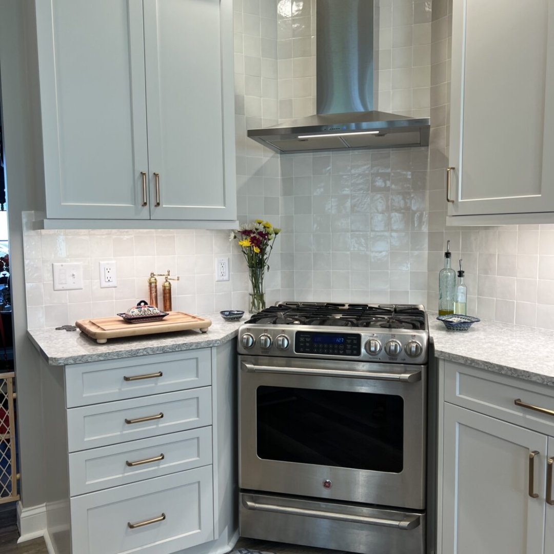 White kitchen cabinets with brass handles, stainless steel range and hood, modern farmhouse kitchen style