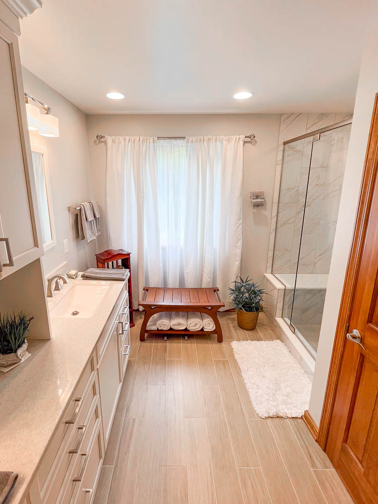Classic bathroom, large cabinet storage, marble shower, light brown modern floor tiles, big window