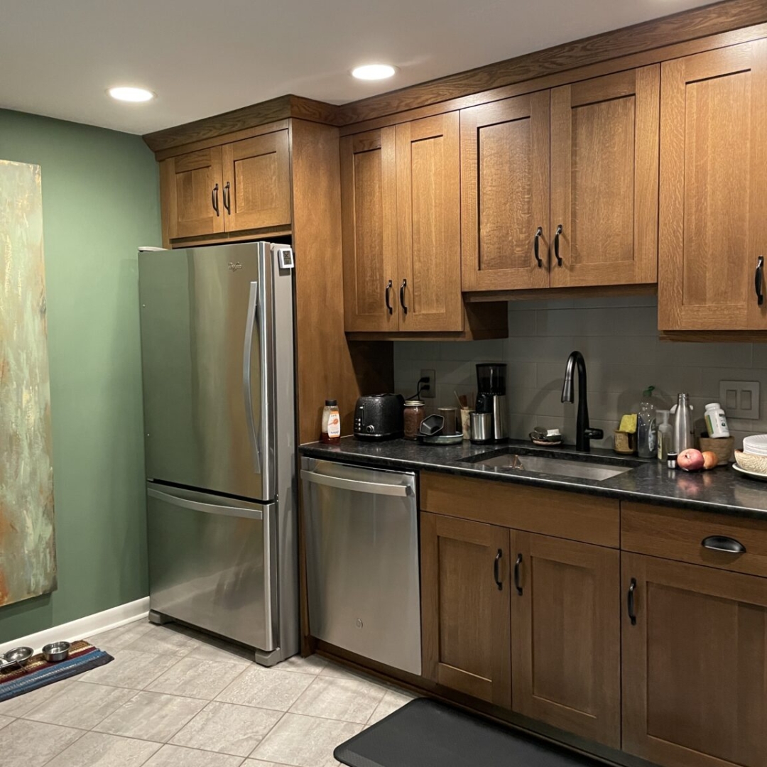 Traditional kitchen remodel, brown wall and base cabinets, black marble countertop, green wall, light color square floor tiles