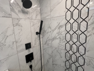 Black shower head idea, hexagonal tile accent, marble shower wall, modern shower inspiration, luxury walk-in shower, geometric tile design, black fixtures inspiration