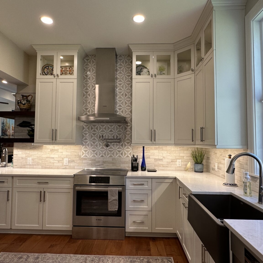 Classic white kitchen counter and stove, white marble countertop, white wall and base cabinets, farming sink, modern white tile backsplash, brown tile floor