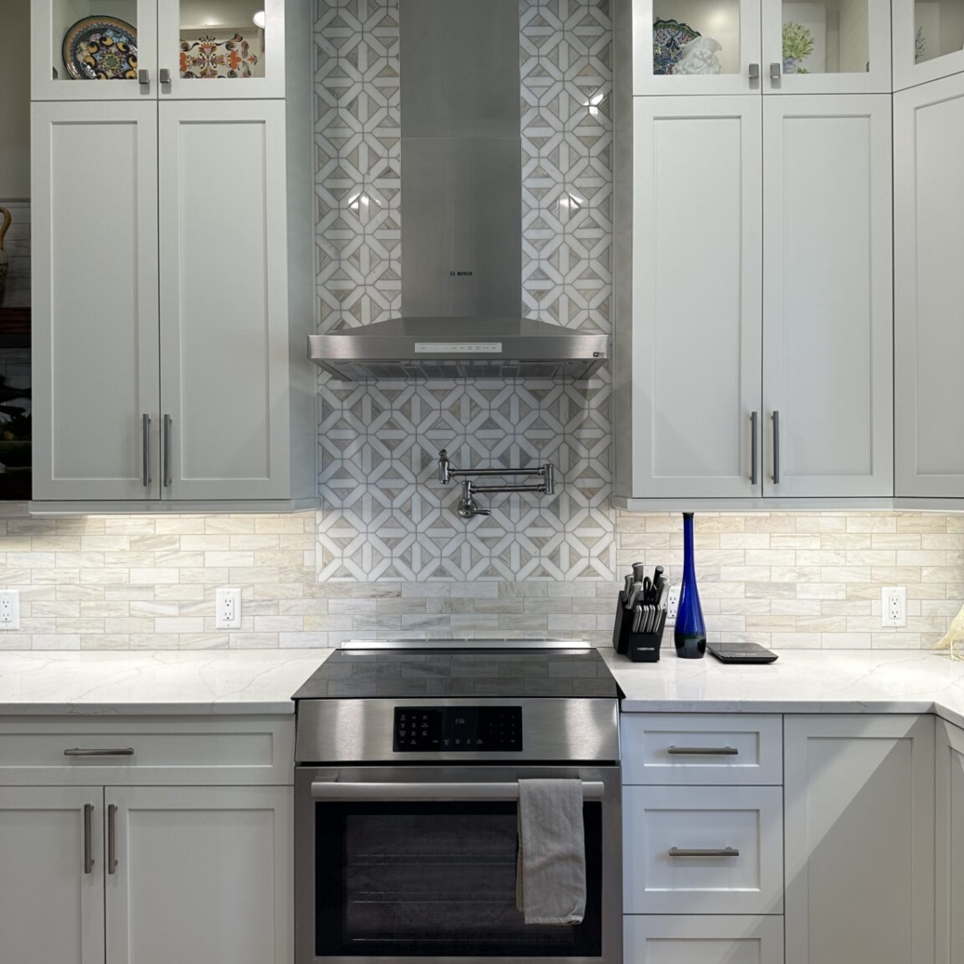 Classic white kitchen stove, white marble countertop, white wall and base cabinets, modern white tile backsplash and original grey backsplash stove, brown tile floor
