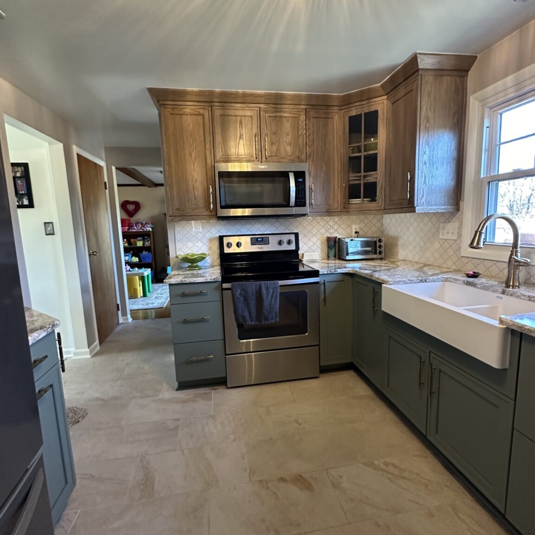 Modern kitchen remodel, dark green base cabinets, brown wall cabinets, grey and white countertop, farming sink, beige rectangular floor tiles