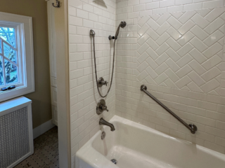 Classic bathroom shower and bathtub, original white wall tiles