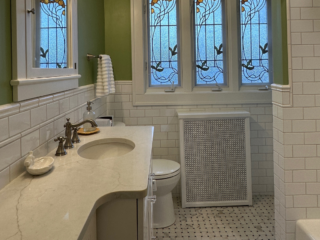 Traditional bathroom, white marble countertop single sink, bathtub, mirror cabinet, original white and grey floor tiles, windows