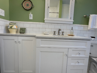 Traditional bathroom, white marble countertop single sink, top mirror cabinet, bottom white cabinet, light green walls, original white and grey floor tiles