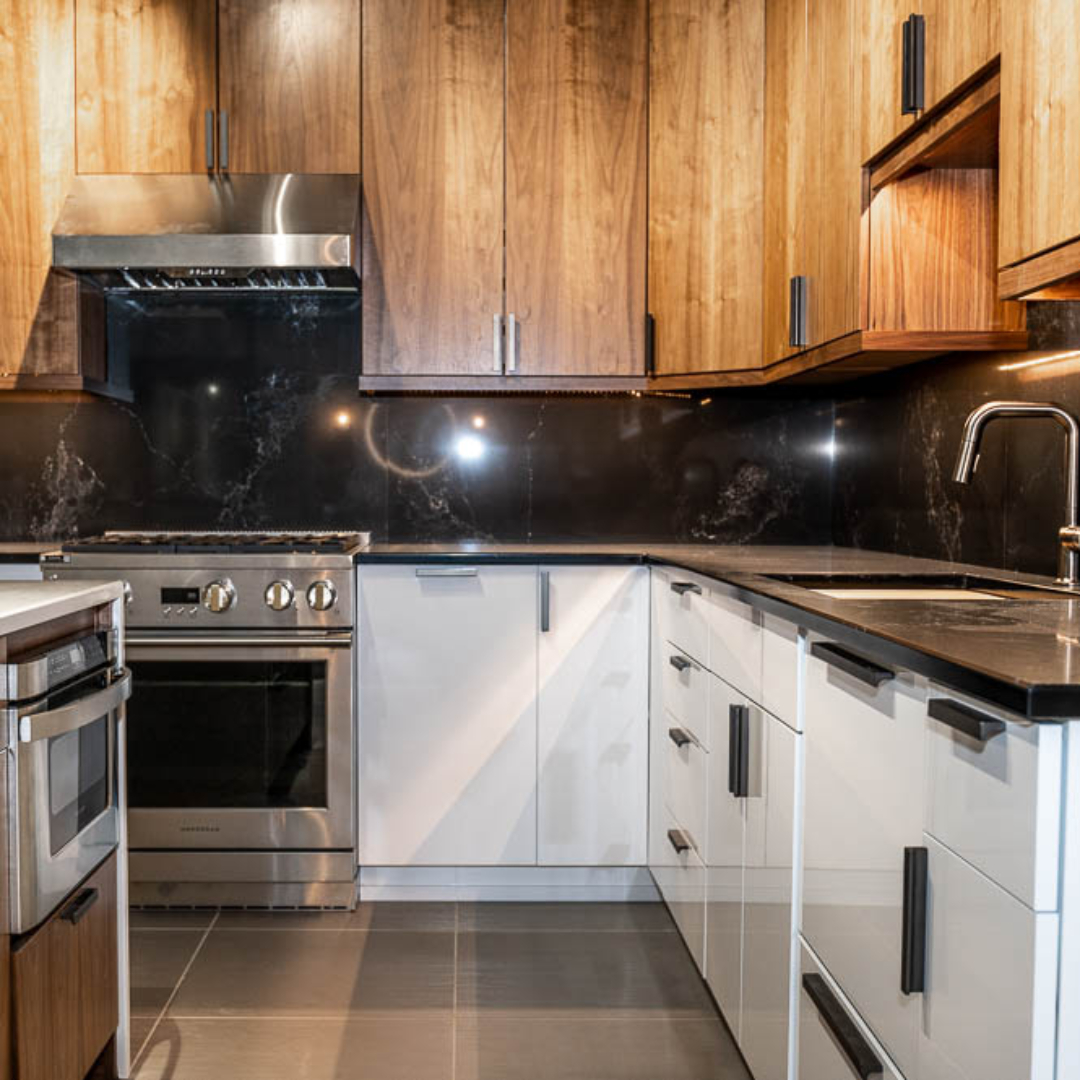 Contemporary kitchen, white marble island with brown cabinet storage, black marble backsplash, brown wall cabinets, white base cabinets, black marble countertop, grey rectangle floor tiles, counter lighting