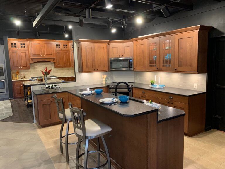 Traditional kitchen, brown wall and base cabinets, black countertops, breakfast bar with sink, beige rectangle floor tiles