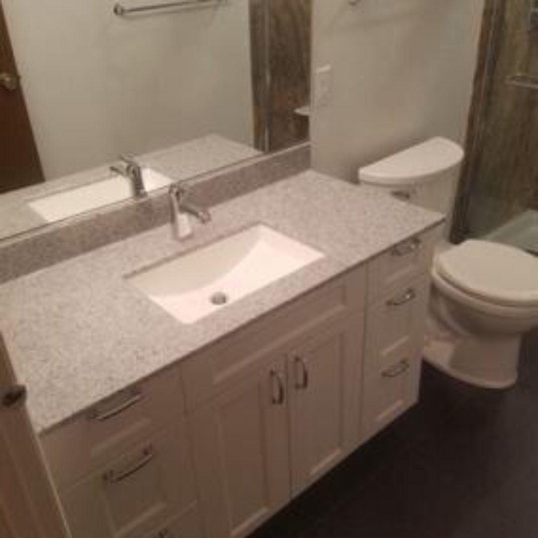 Classic bathroom, small sink, marble countertop, white cabinets, mirror, toilet