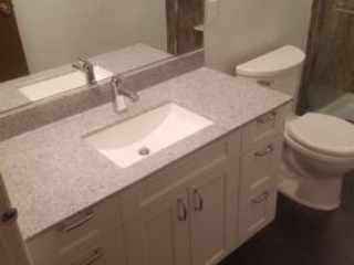 Classic bathroom, small sink, marble countertop, white cabinets, mirror, toilet