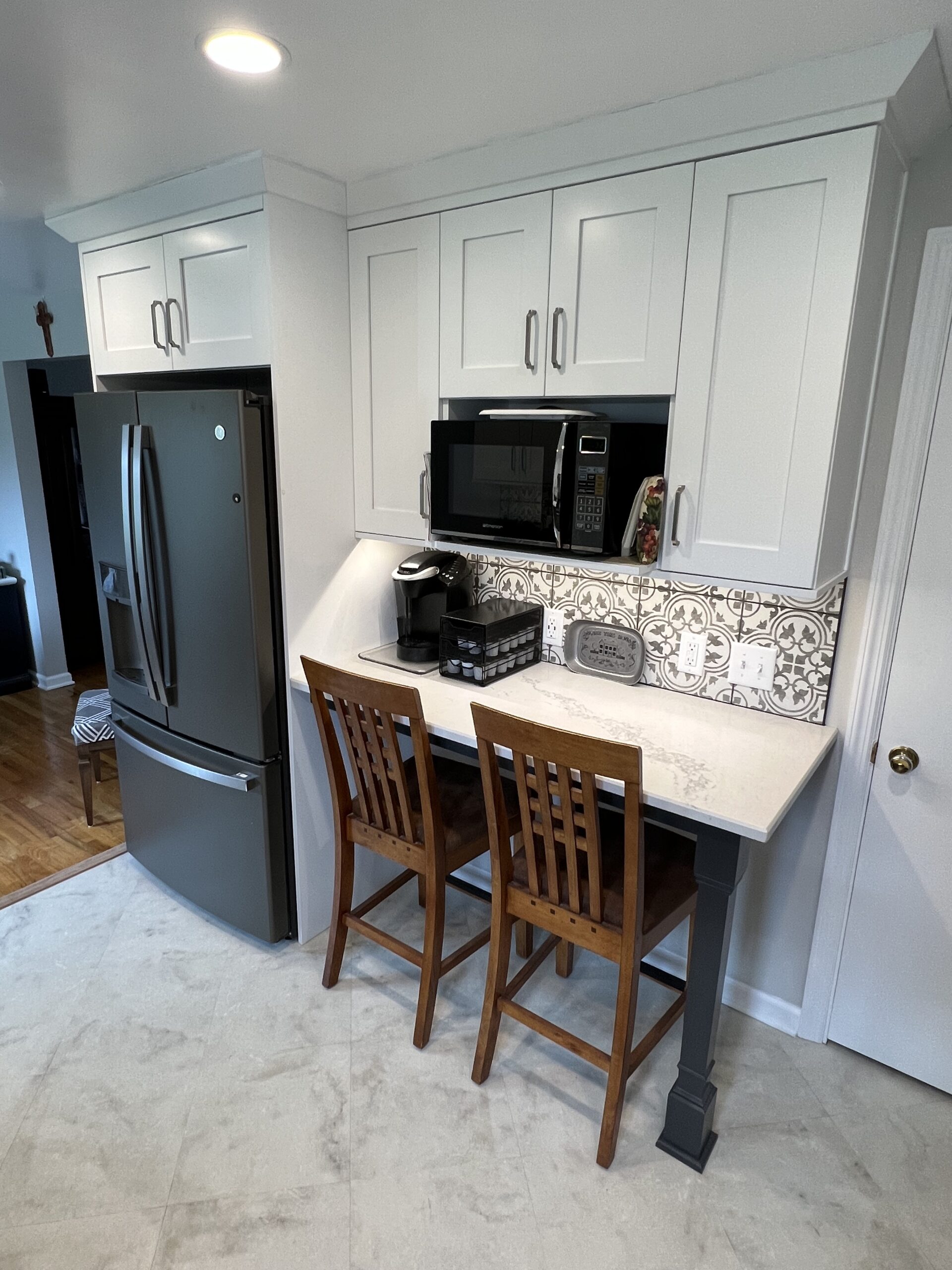 Modern black and white kitchen, white wall cabinets, white marble countertops, backsplash arabesque design, large square light color floor tiles
