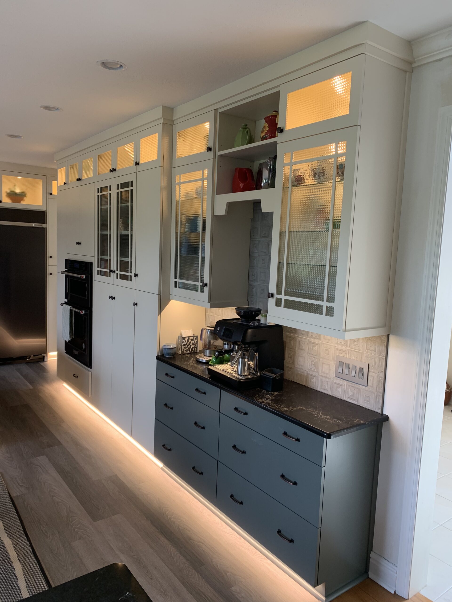 Modern blue kitchen remodeling, black marble counter, blue base cabinets, white closet storage, cabinet floor lighting
