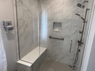 Modern bathroom, white marble tile shower walls, grey floor shower tiles, shower seat