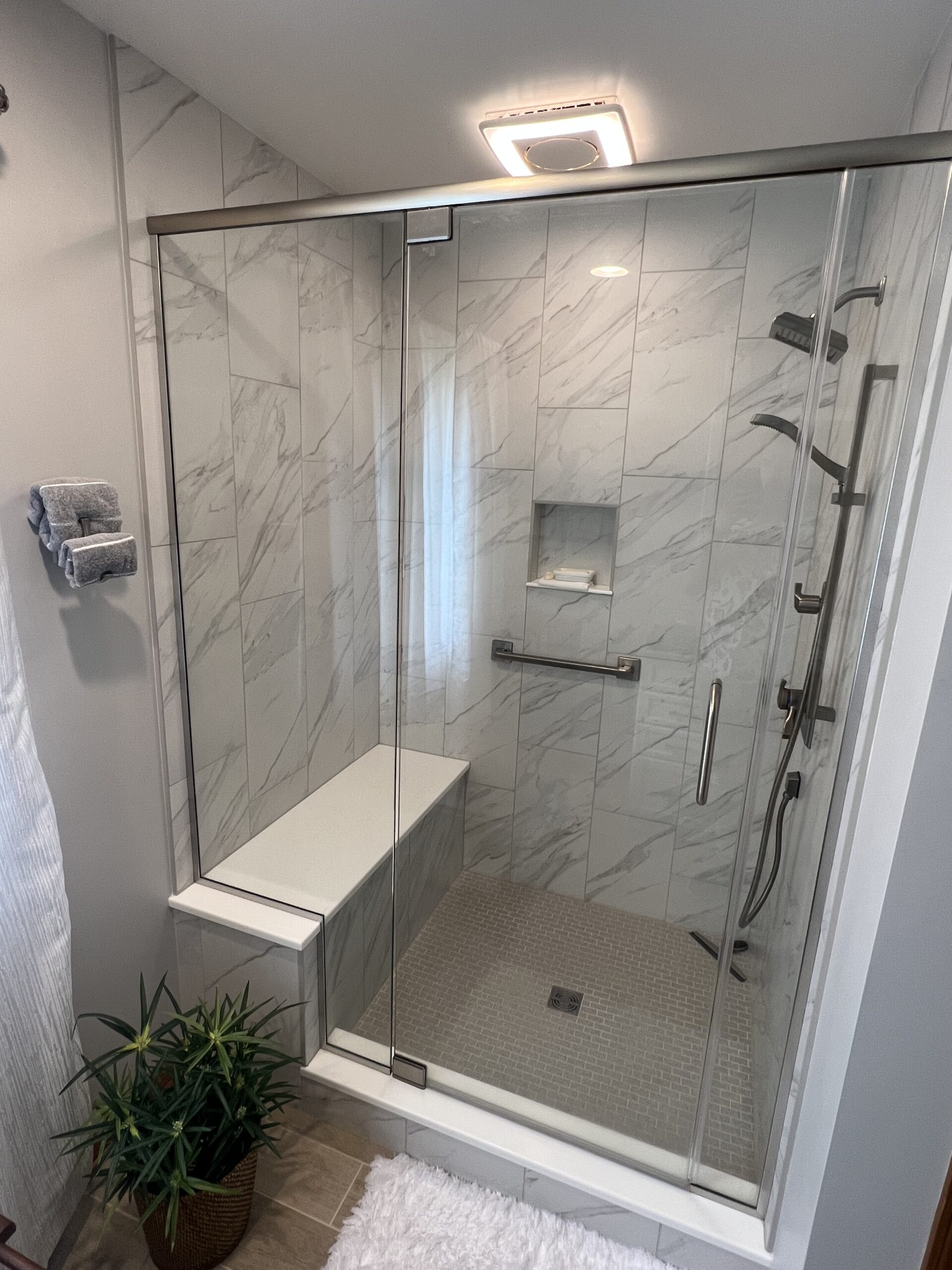 Modern bathroom, white marble tile shower walls, grey floor shower tiles, shower seat