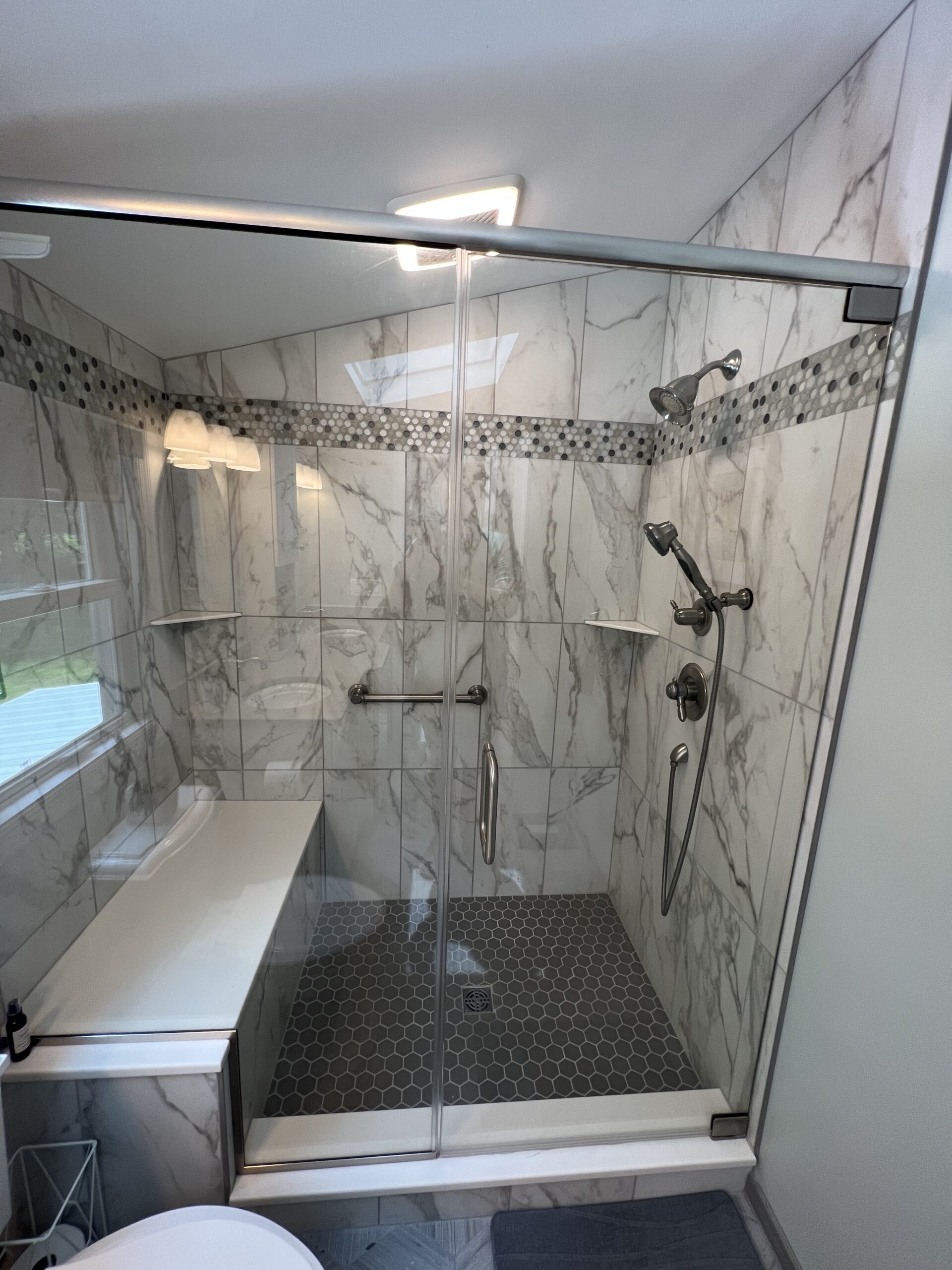 Classic bathroom, black and white marble shoer walls, dark shower floor tiles, shelves, grey shaded marble band