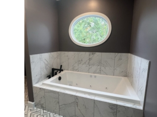 Spa-inspired bathroom, spa tub inspiration, marble tile bathroom, oval window design, luxury bathroom tub, contemporary bath idea, relaxing bath design