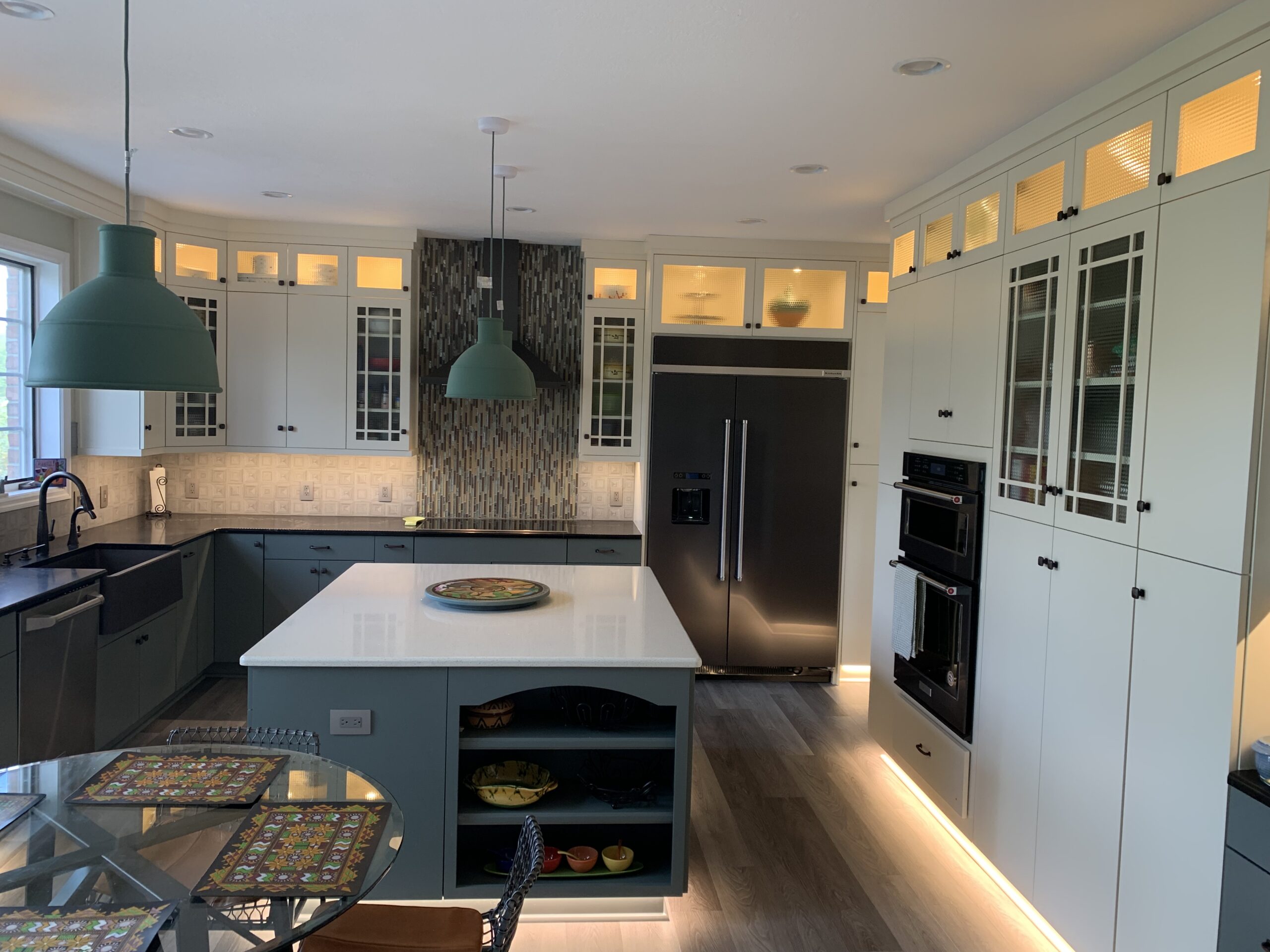 Modern blue kitchen remodeling, square island with storage and white marble countertop, black marble counter, blue base cabinets, white closet storage, black and white tile backsplash, island and cabinet floor lighting
