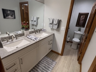 Classic bathroom, double sink, grey marble countertop, white cabinets, large mirror, modern brown floor tiles