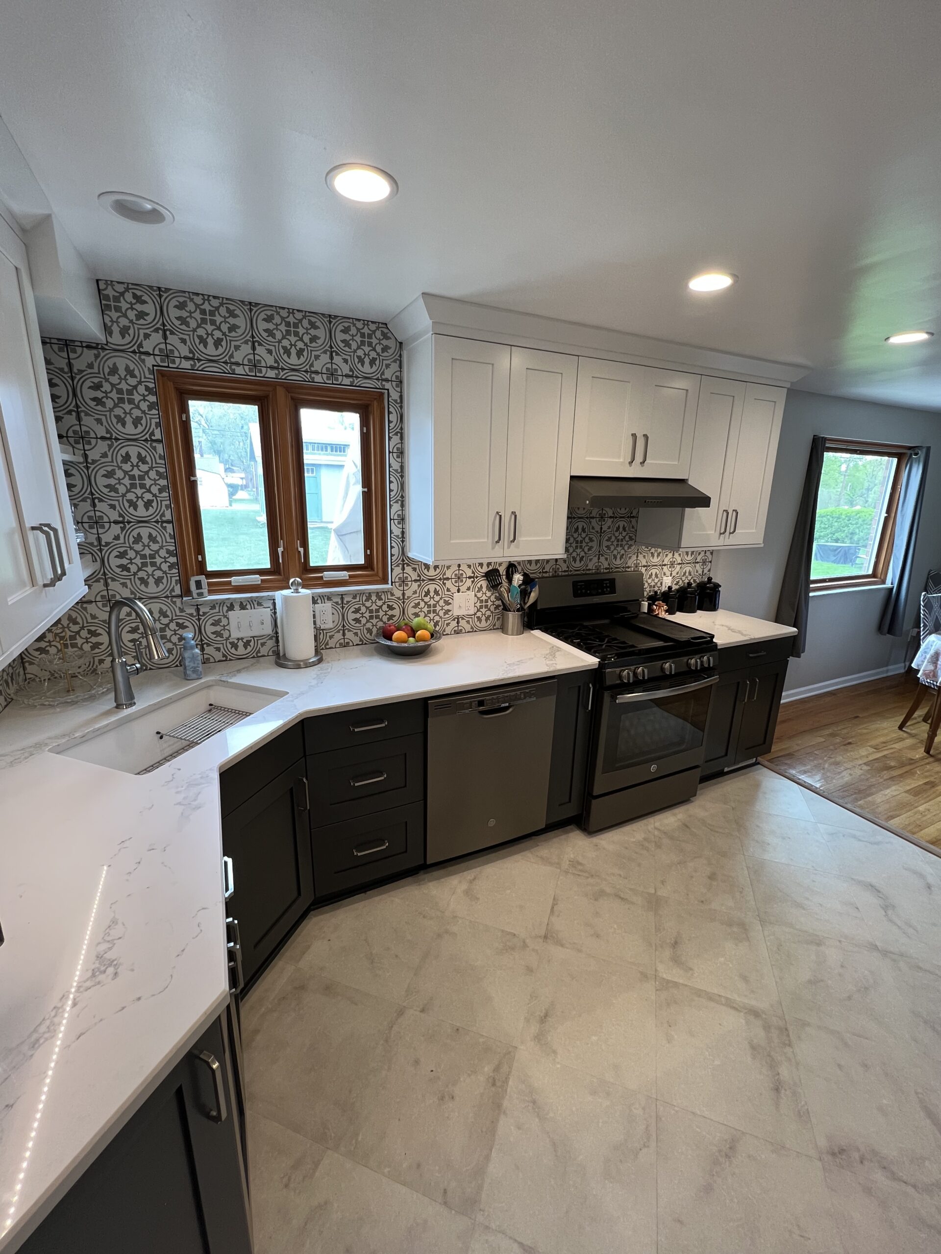 Modern black and white kitchen, white wall cabinets, black base cabinets, white marble countertops, backsplash arabesque design