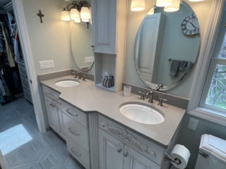 Traditional bathroom, vintage double sink, grey marble countertop, two round-shaped mirrors, window, toilet