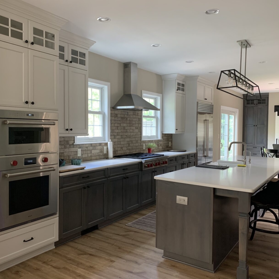 Modern kitchen remodel, island with grey cabinets and white countertop, white wall cabinets, dark grey base cabinets, subway tile backsplash, traditional cooker hood